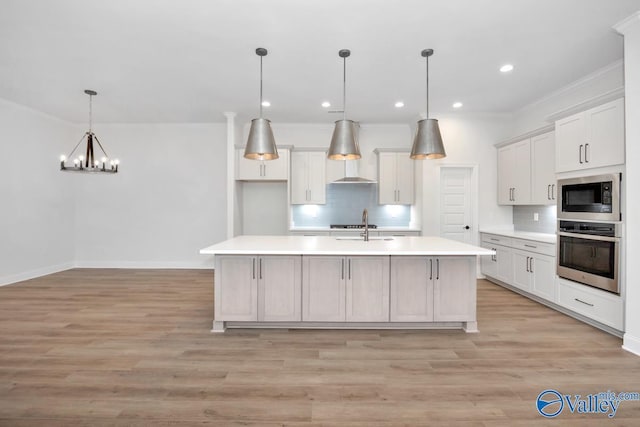 kitchen featuring built in microwave, a kitchen island with sink, white cabinets, and oven