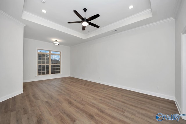 unfurnished room featuring a raised ceiling, crown molding, ceiling fan, and dark hardwood / wood-style flooring