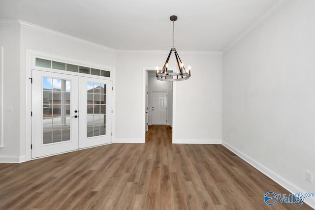 unfurnished dining area featuring french doors, ornamental molding, dark wood-type flooring, and a notable chandelier