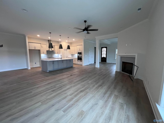 kitchen featuring wall chimney exhaust hood, a center island, hanging light fixtures, and white cabinets