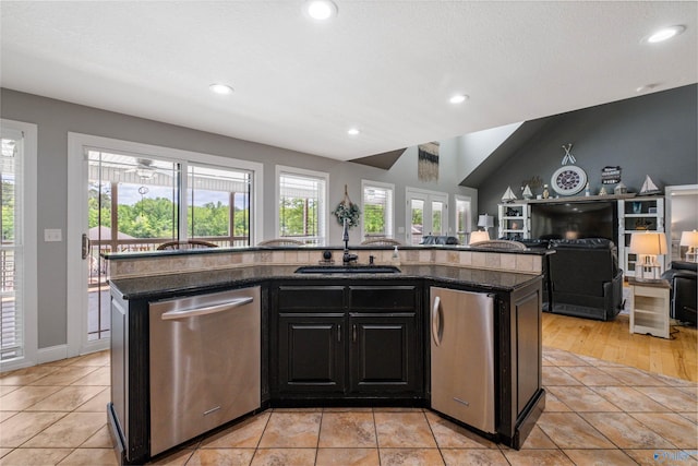 kitchen featuring a sink, dark stone counters, recessed lighting, stainless steel dishwasher, and a center island with sink