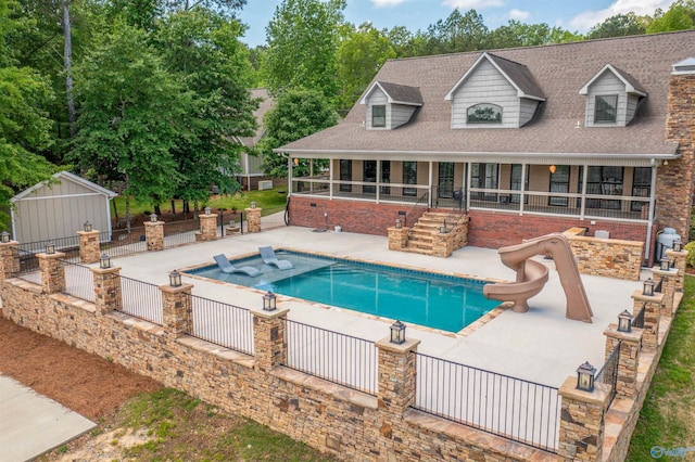 pool featuring fence, a water slide, and a patio