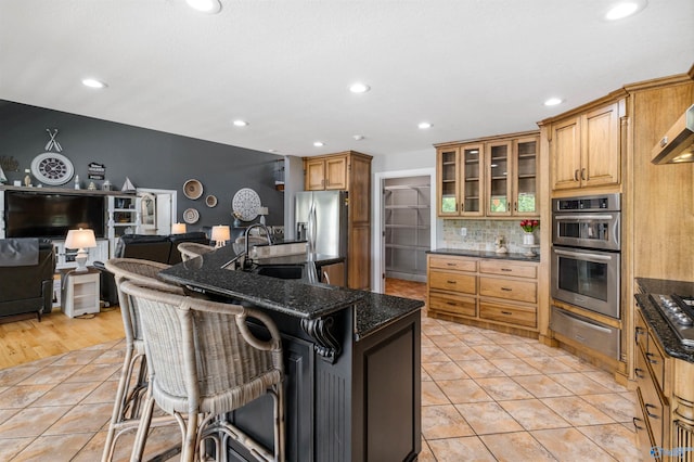 kitchen featuring appliances with stainless steel finishes, a sink, a breakfast bar area, decorative backsplash, and a warming drawer