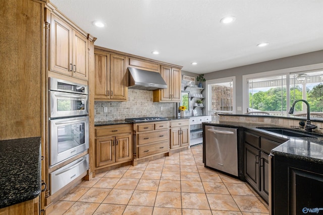kitchen with a sink, wall chimney exhaust hood, stainless steel appliances, tasteful backsplash, and a warming drawer