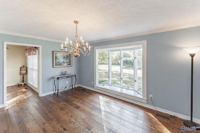 unfurnished dining area with ornamental molding, a chandelier, a textured ceiling, and dark hardwood / wood-style floors