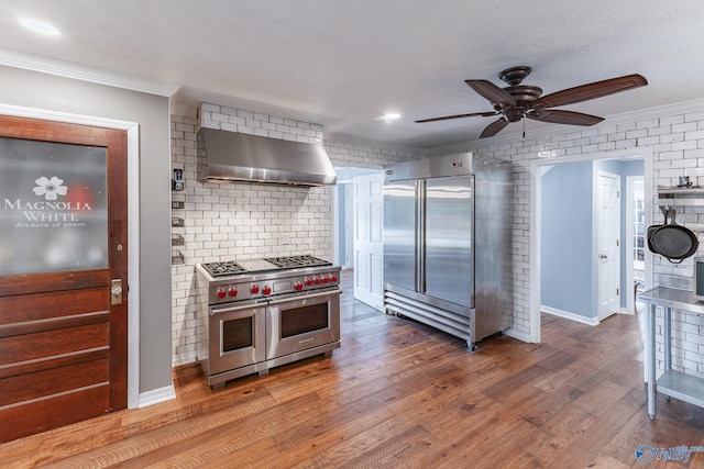 kitchen featuring crown molding, wall chimney range hood, hardwood / wood-style flooring, high quality appliances, and ceiling fan