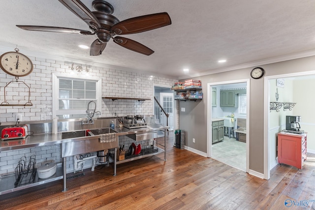 kitchen featuring stainless steel counters, crown molding, a textured ceiling, dark wood-type flooring, and ceiling fan