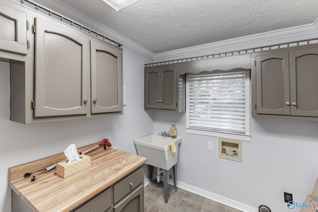 washroom featuring ornamental molding, a textured ceiling, cabinets, and hookup for a washing machine