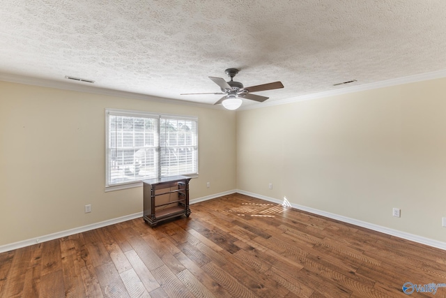 empty room with dark wood-type flooring, a textured ceiling, and ornamental molding