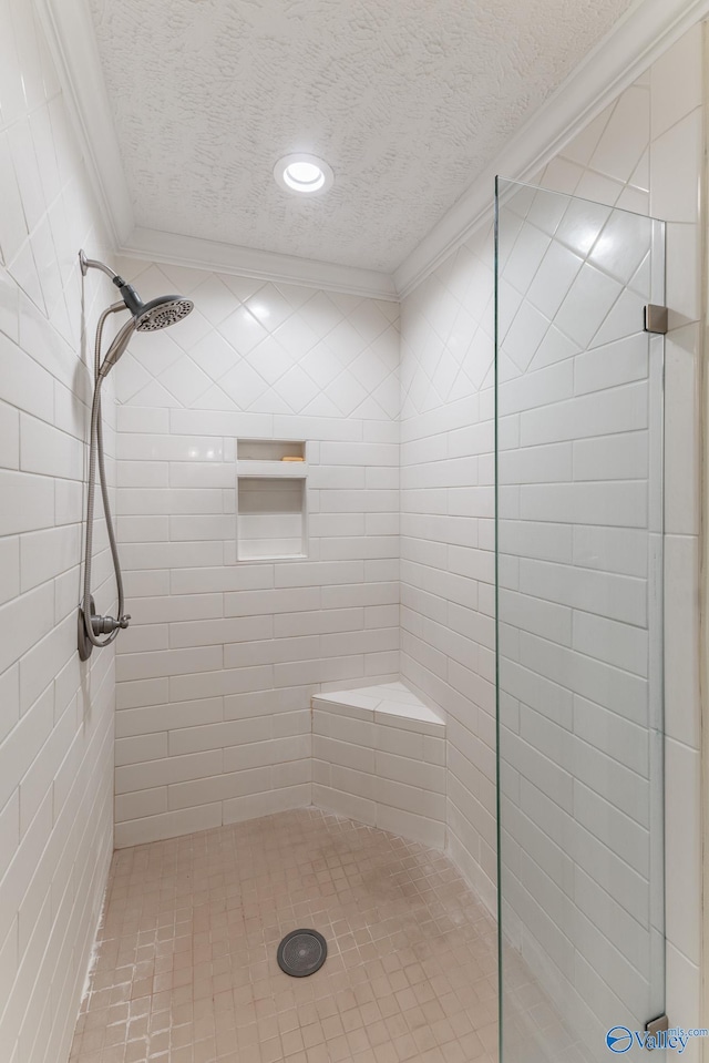 bathroom with a textured ceiling, tiled shower, and crown molding