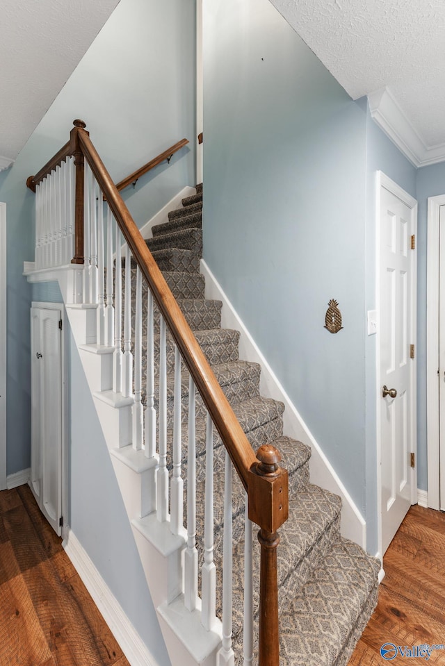 stairway featuring a textured ceiling, hardwood / wood-style flooring, and crown molding