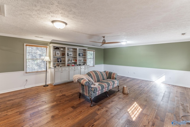 sitting room featuring dark hardwood / wood-style flooring, a textured ceiling, crown molding, and ceiling fan