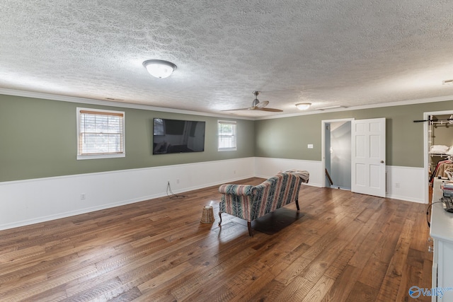 living area with wood-type flooring, ornamental molding, and a textured ceiling