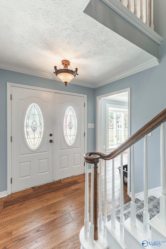 entryway with hardwood / wood-style floors, crown molding, and a textured ceiling