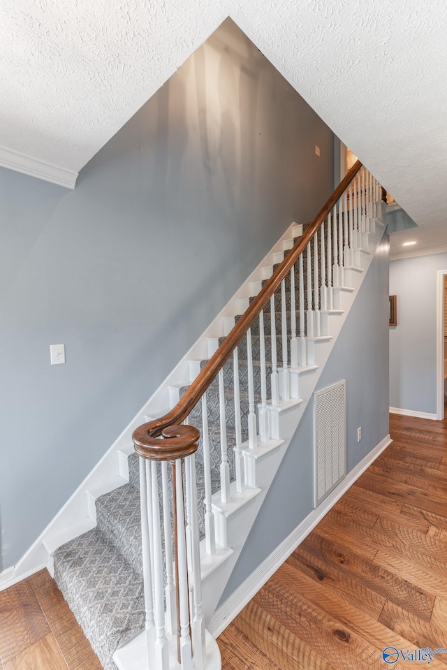 staircase with hardwood / wood-style floors and a textured ceiling