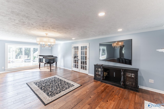 living room featuring wood-type flooring, a textured ceiling, french doors, and ornamental molding