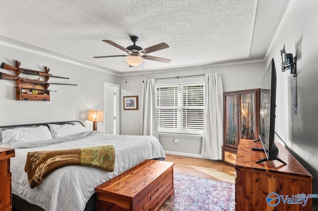 bedroom with crown molding, a textured ceiling, light wood-style floors, ceiling fan, and baseboards