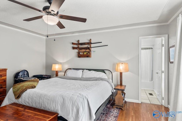 bedroom featuring a textured ceiling, visible vents, wood finished floors, ceiling fan, and ornamental molding