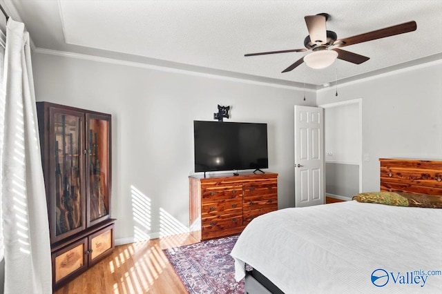 bedroom featuring a textured ceiling, crown molding, wood-type flooring, and ceiling fan