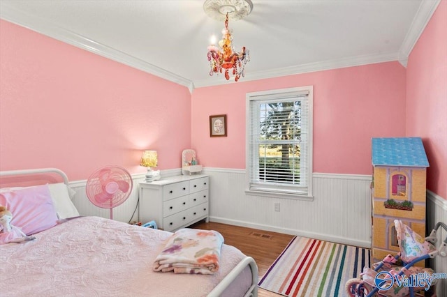 bedroom with a wainscoted wall, wood finished floors, a chandelier, and ornamental molding