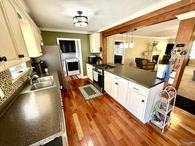 kitchen featuring stainless steel gas stove, a sink, dark countertops, dark wood finished floors, and crown molding