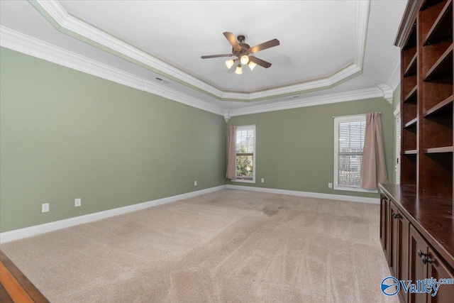 unfurnished room featuring ceiling fan, a raised ceiling, crown molding, and light carpet