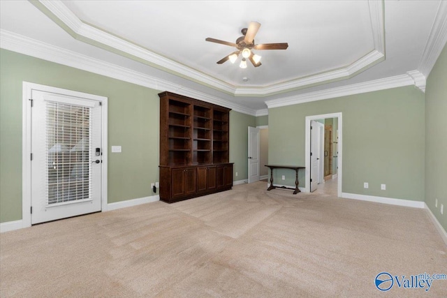 interior space with ceiling fan, ornamental molding, light carpet, and a tray ceiling