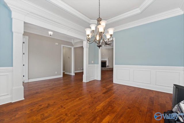 unfurnished dining area with a notable chandelier, dark hardwood / wood-style flooring, crown molding, and a tray ceiling