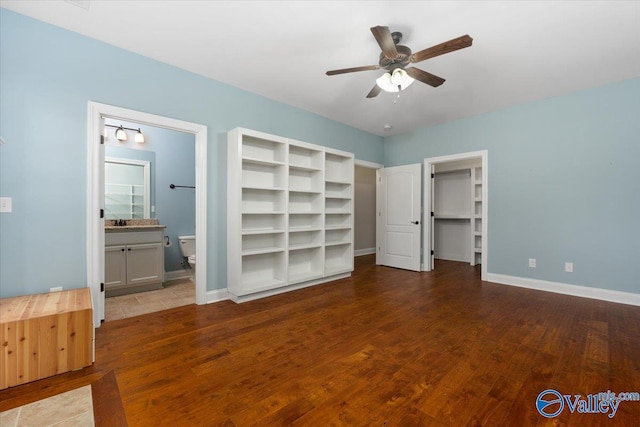 unfurnished bedroom featuring hardwood / wood-style flooring, ceiling fan, a spacious closet, and connected bathroom