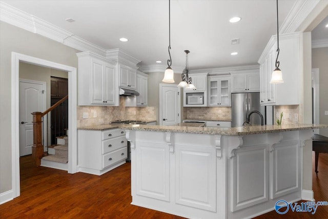 kitchen with white cabinets, dark hardwood / wood-style flooring, stainless steel fridge, pendant lighting, and white microwave