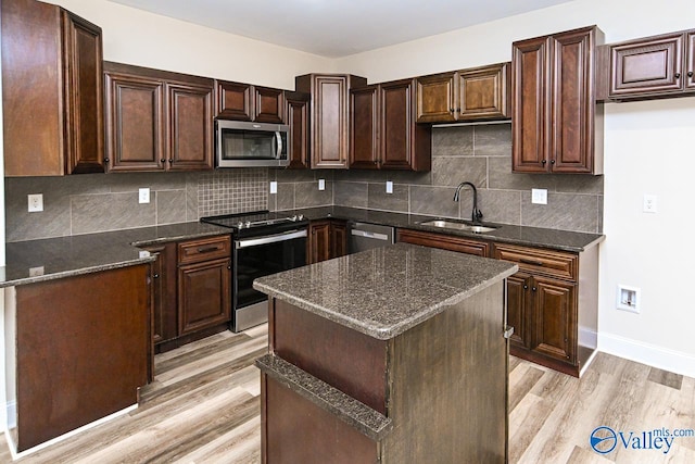 kitchen featuring decorative backsplash, appliances with stainless steel finishes, light wood-type flooring, sink, and a kitchen island