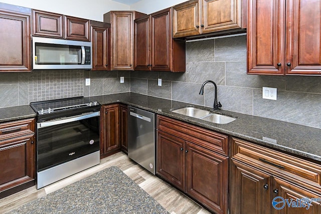 kitchen featuring appliances with stainless steel finishes, tasteful backsplash, light hardwood / wood-style flooring, and sink