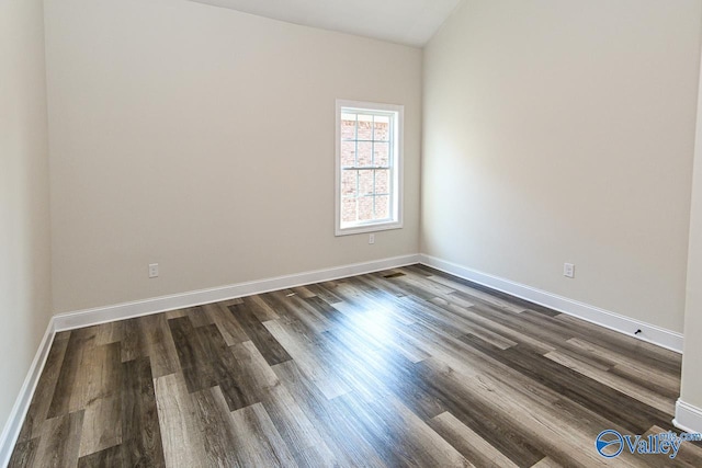 unfurnished room with vaulted ceiling and dark wood-type flooring