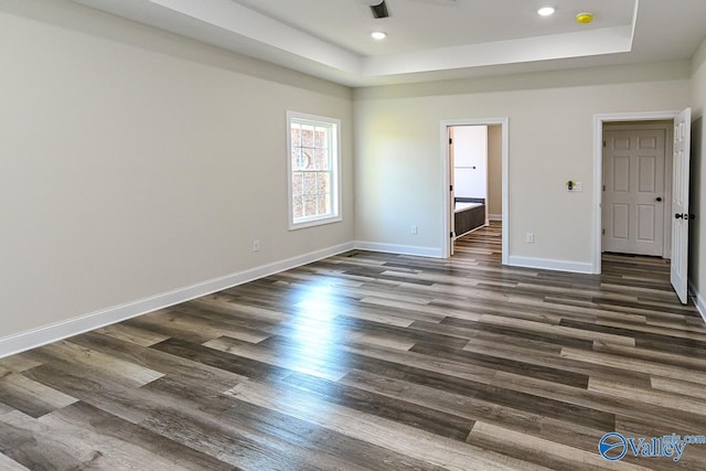 unfurnished bedroom with a raised ceiling, dark hardwood / wood-style floors, and ensuite bath