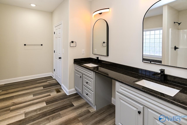 bathroom with walk in shower, vanity, and hardwood / wood-style flooring