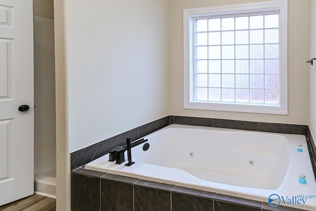 bathroom featuring hardwood / wood-style floors, tiled bath, and a wealth of natural light