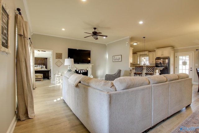 living room with ceiling fan, ornamental molding, and light wood-type flooring