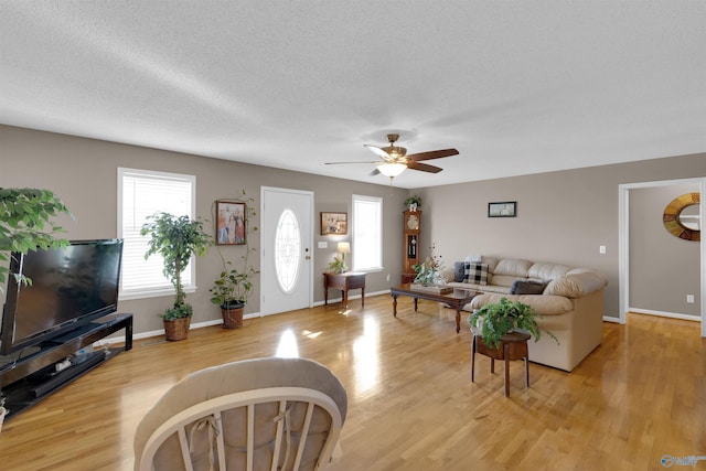 living room with ceiling fan, light hardwood / wood-style floors, and a textured ceiling