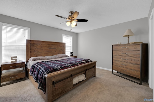 bedroom with ceiling fan, light colored carpet, and a textured ceiling