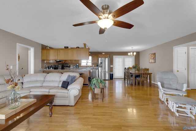 living room with light hardwood / wood-style flooring and ceiling fan with notable chandelier