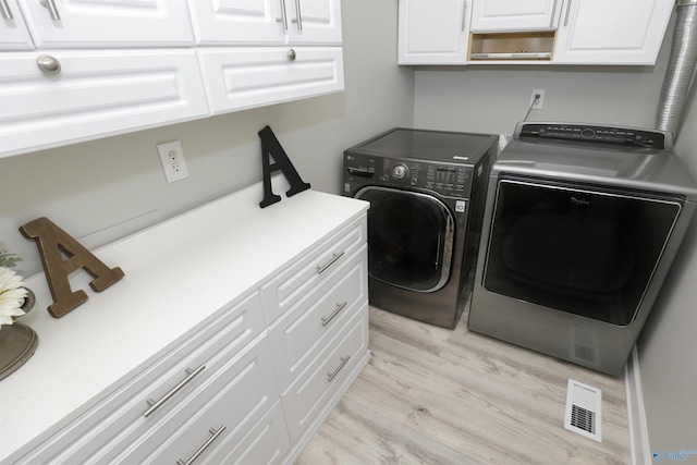 laundry area with cabinets, washer and clothes dryer, and light hardwood / wood-style floors