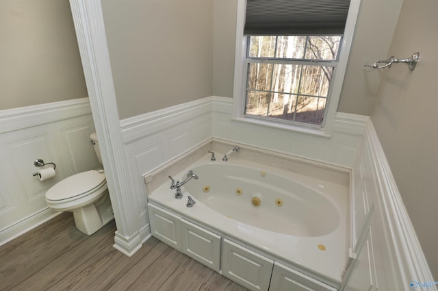 bathroom with hardwood / wood-style flooring, toilet, and a tub to relax in