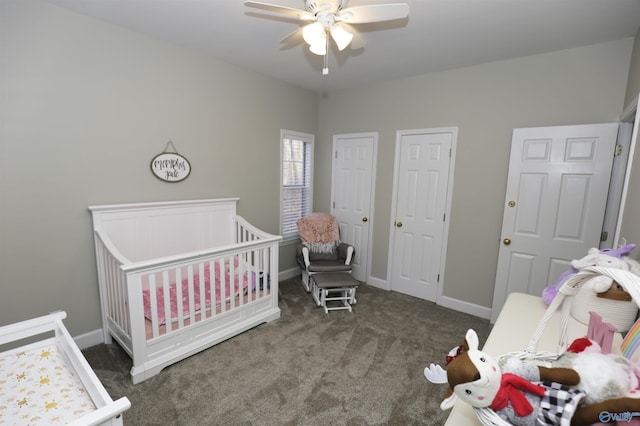 bedroom featuring a nursery area, ceiling fan, two closets, and dark colored carpet