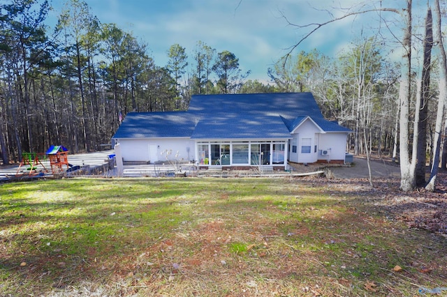 back of house featuring a lawn and a playground