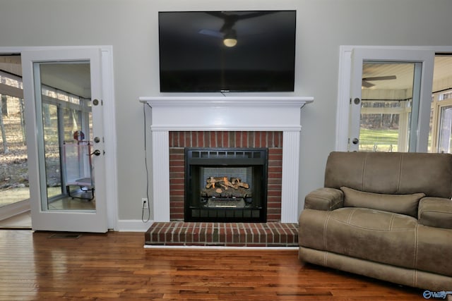 living room featuring a brick fireplace and dark wood-type flooring