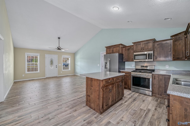 kitchen featuring dark brown cabinetry, stainless steel appliances, ceiling fan, a center island, and light hardwood / wood-style floors