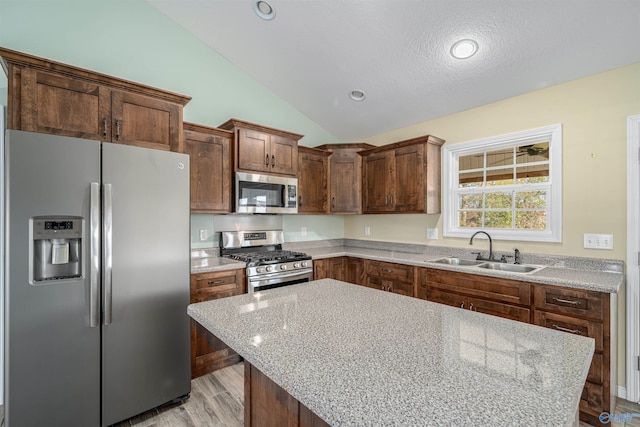 kitchen featuring light stone countertops, a textured ceiling, stainless steel appliances, vaulted ceiling, and sink