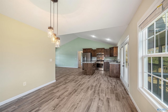 kitchen featuring pendant lighting, stainless steel appliances, vaulted ceiling, and a healthy amount of sunlight