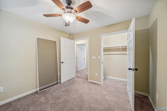 unfurnished bedroom featuring light carpet, a textured ceiling, a closet, and ceiling fan