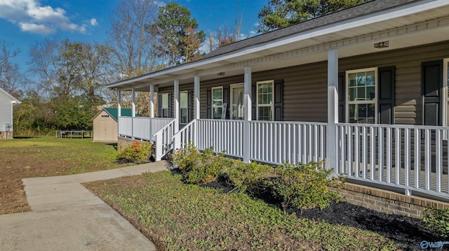 view of front of house with covered porch, a front lawn, and a storage shed